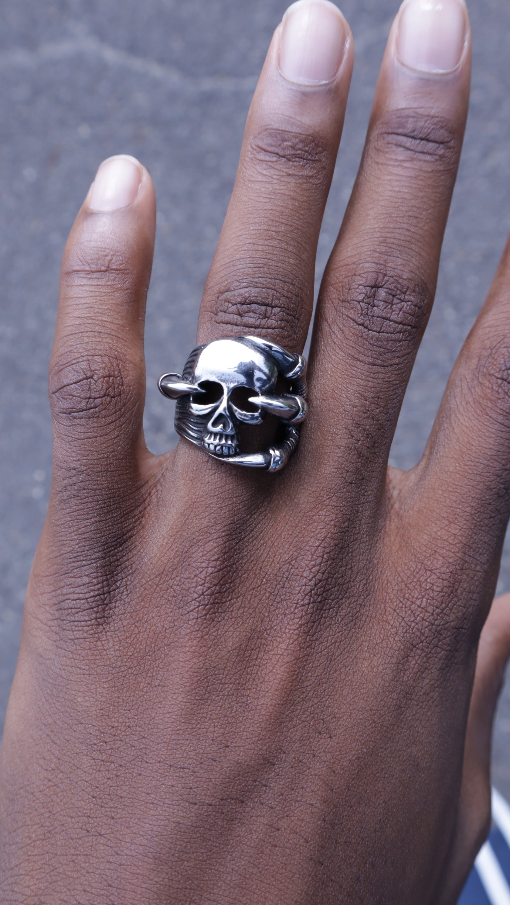 Silver skull ring on a person's finger with a blurred background